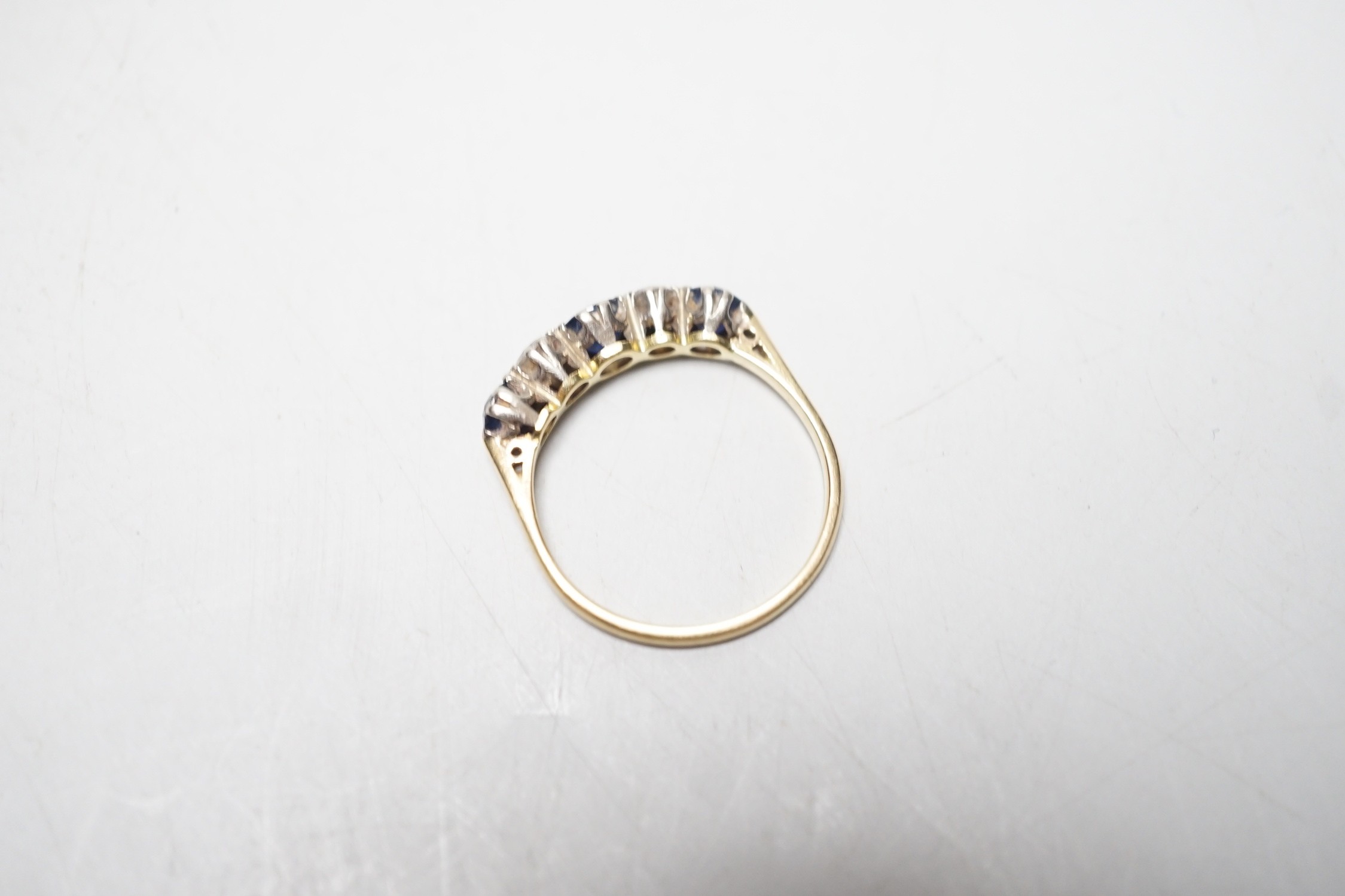 A modern 18ct gold, three stone sapphire and two stone diamond set half hoop ring, size R, gross weight 3.1 grams.